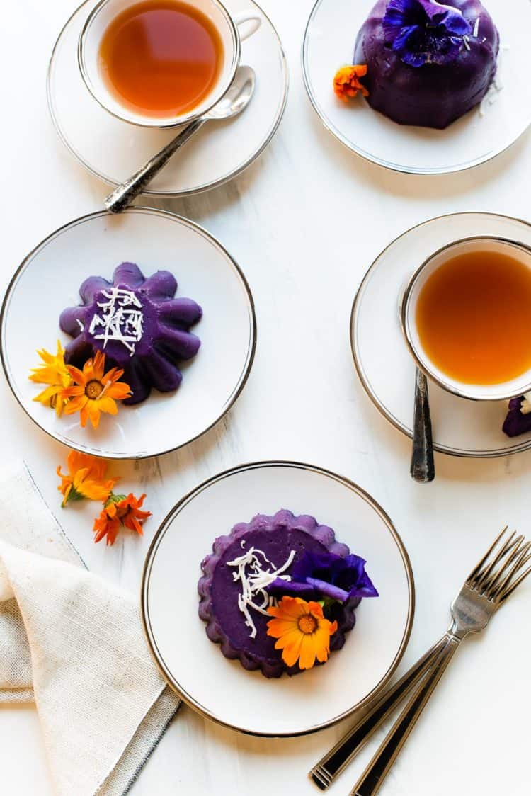 Ube Halaya molded into individual cakes, garnished with shredded coconut and edible flowers.