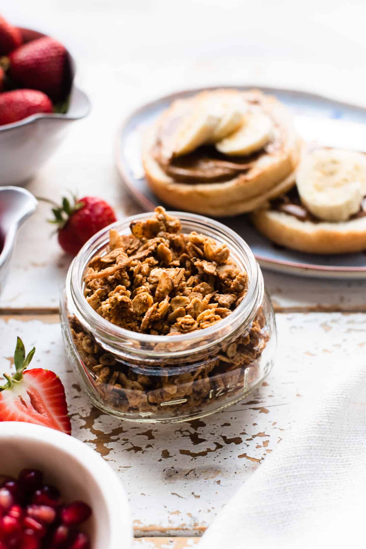 Almond Butter Granola in a glass jar with almond butter and banana toast in background