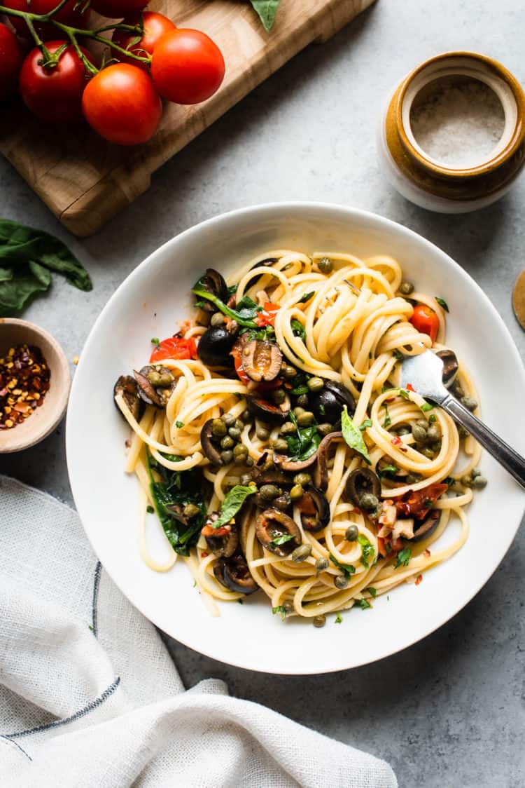 White dish filled with Vegetarian Pasta Puttanesca twirled around a fork.