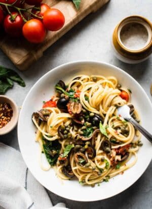 White dish filled with Vegetarian Pasta Puttanesca twirled around a fork.