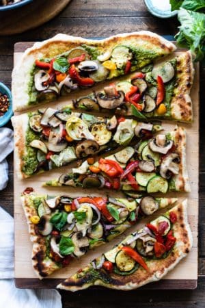 Slices of grilled vegetable pizza on a wooden cutting board.