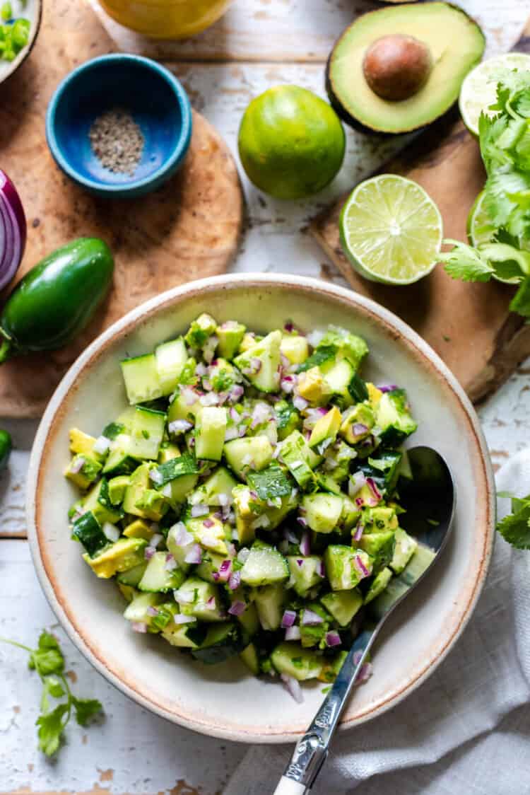 A bowl of Avocado Cucumber Salad with red onion, lime juice, and jalapeños.