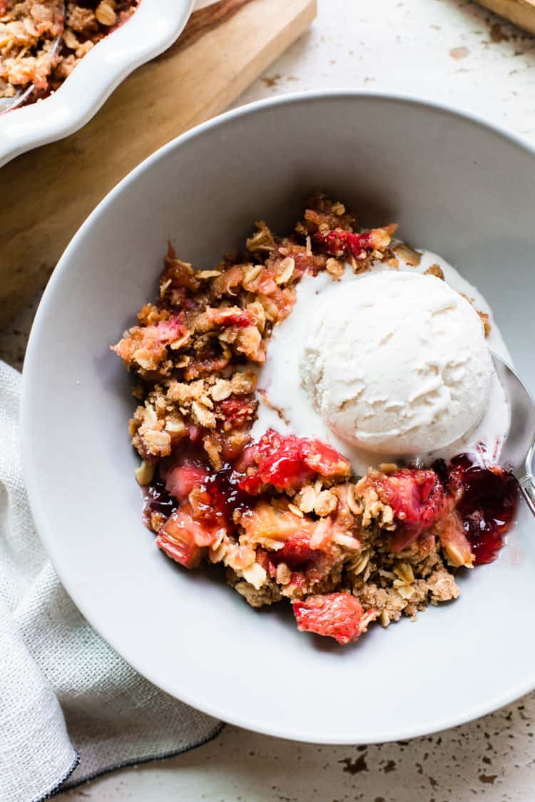 Strawberry Rhubarb Crisp in a light gray bowl with a scoop of ice cream.