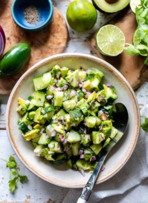 A bowl of Avocado Cucumber Salad with red onion, lime juice, and jalapeños.