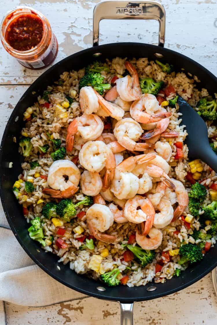 Adding shrimp to spicy fried rice in a nonstick skillet.