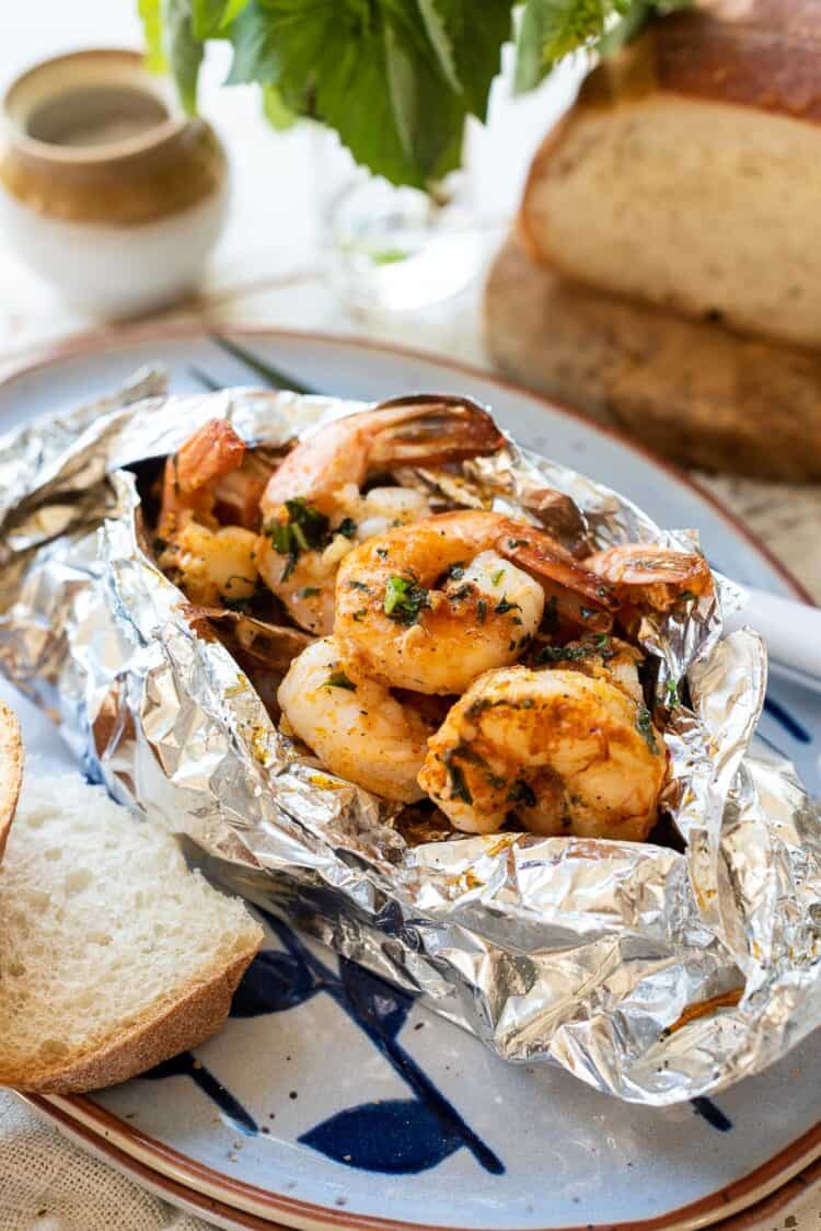 Grilled Shrimp Packets cook shrimp in a foil packet with herbed compound butter and bread on the side.