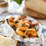 Grilled Shrimp Packets cook shrimp in a foil packet with herbed compound butter and bread on the side.