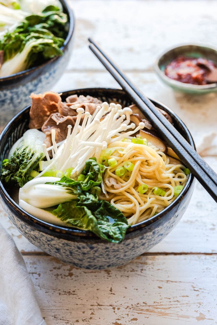 Ramen in a blue bowl with chopsticks.