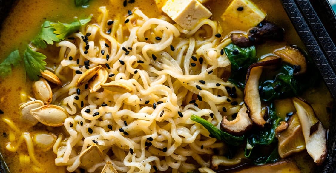 Pumpkin ramen in a black bowl.