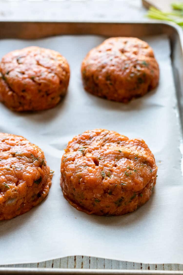 Thai Salmon Burger patties on a parchment-lined baking sheet.