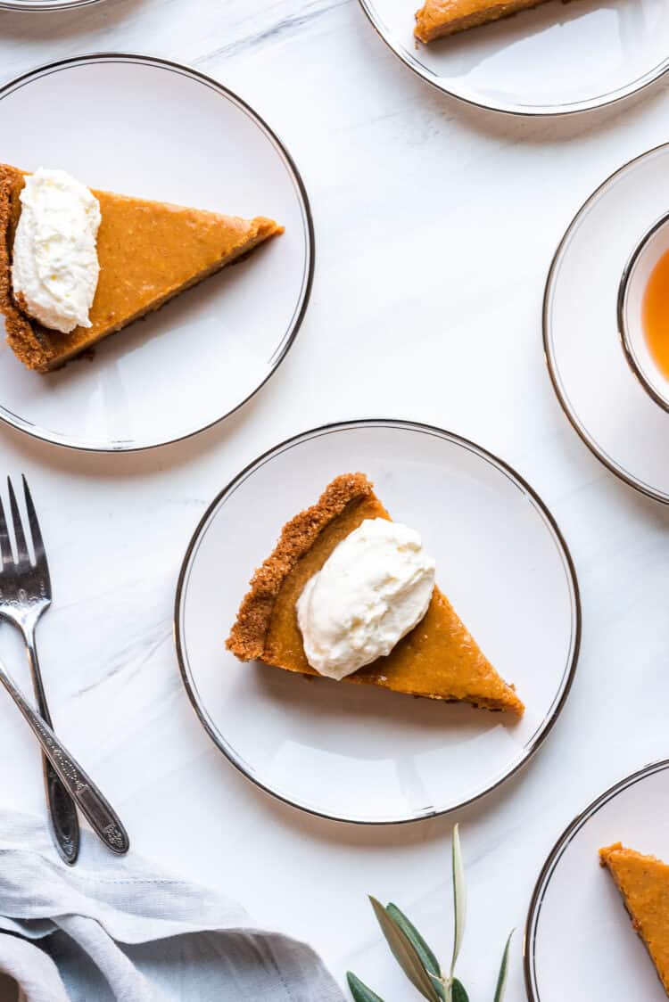 Slices of Cassava Pumpkin Pie and whipped cream on white plates.