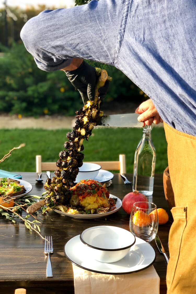 Carving grilled brussels sprouts off the stalk at the Cobram Estate Harvest Tour 2019.