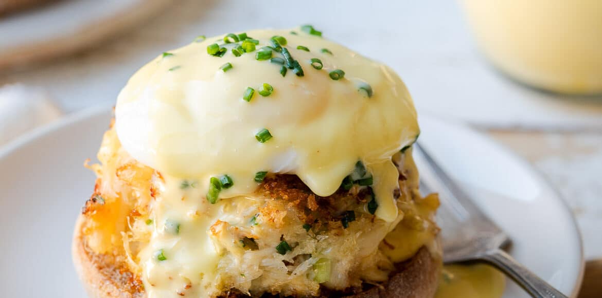 Crab Cake Benedict on white plate with hollandaise sauce.