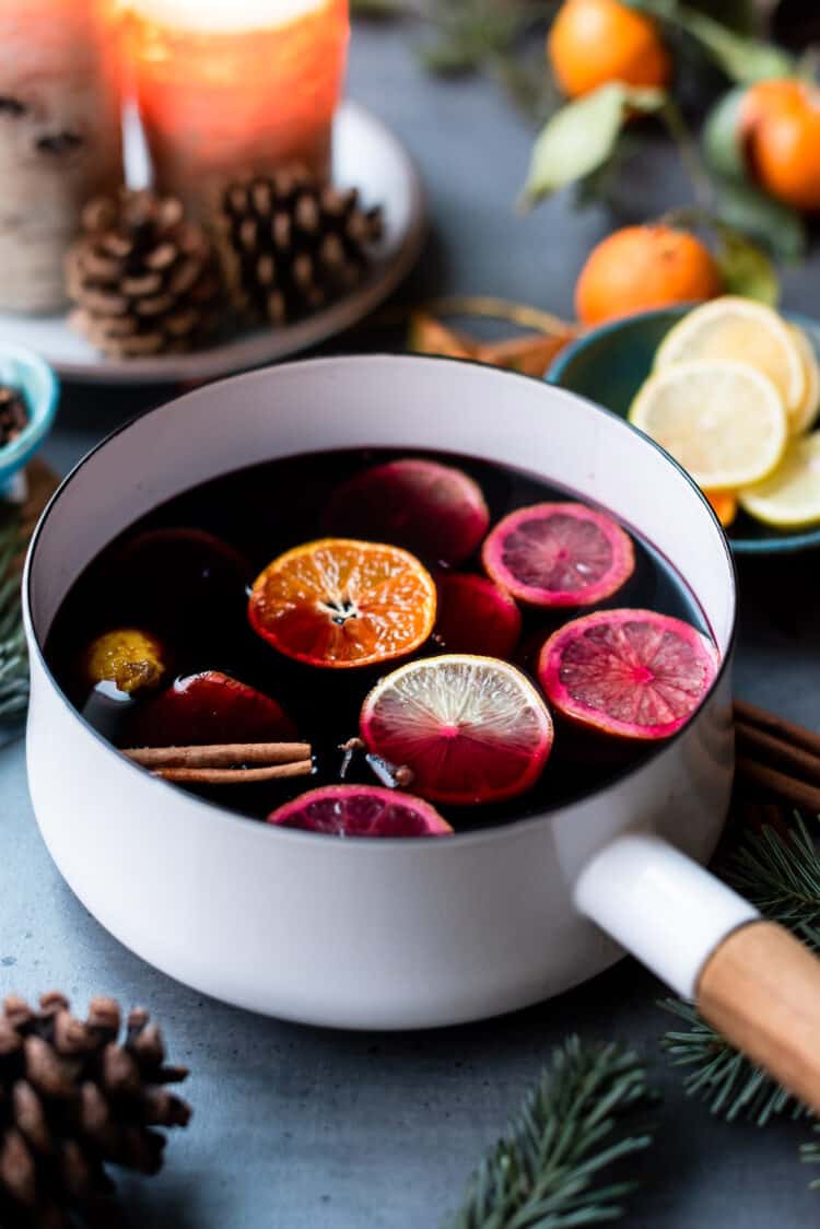 Mulled Wine in a white pan with orange, lemon and spices.