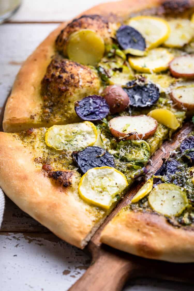 Close up shot of a slice of Potato Pesto Pizza with Brussels Sprouts and Yellow Squash.