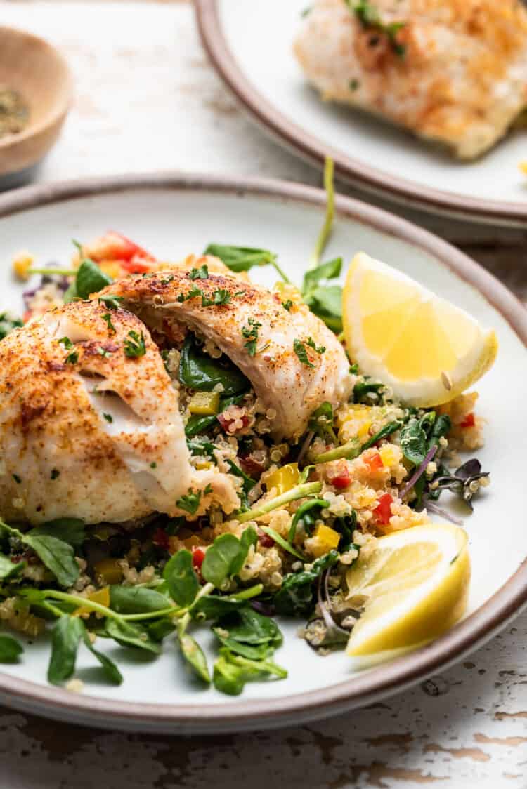 Quinoa Stuffed Alaska Sole sliced in half to show filling of quinoa, spinach, and peppers.