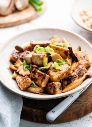 Filipino Crispy Tofu and Mushroom Adobo in a serving dish and garnished with scallions.