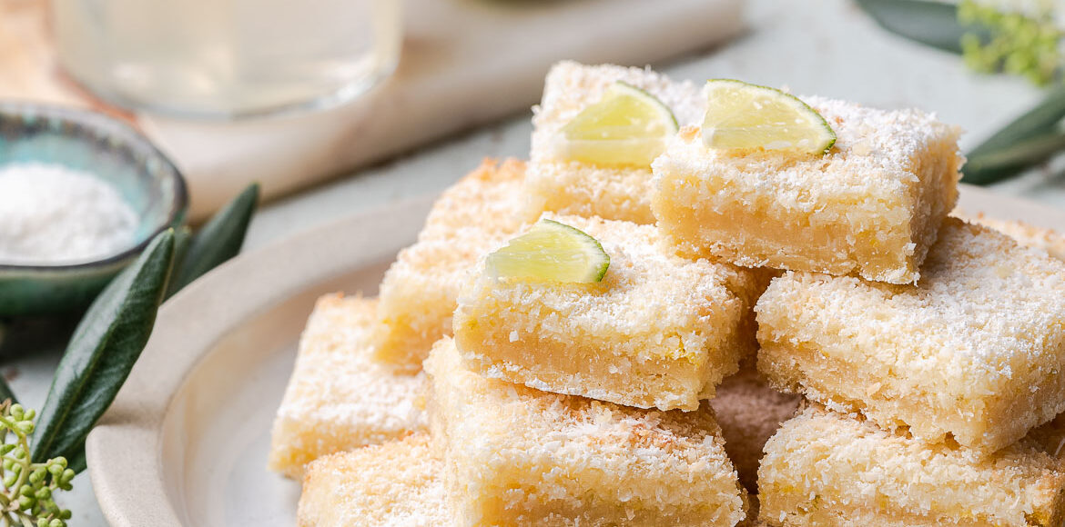 A stack of margarita bars on a white plate with a margarita in the background.
