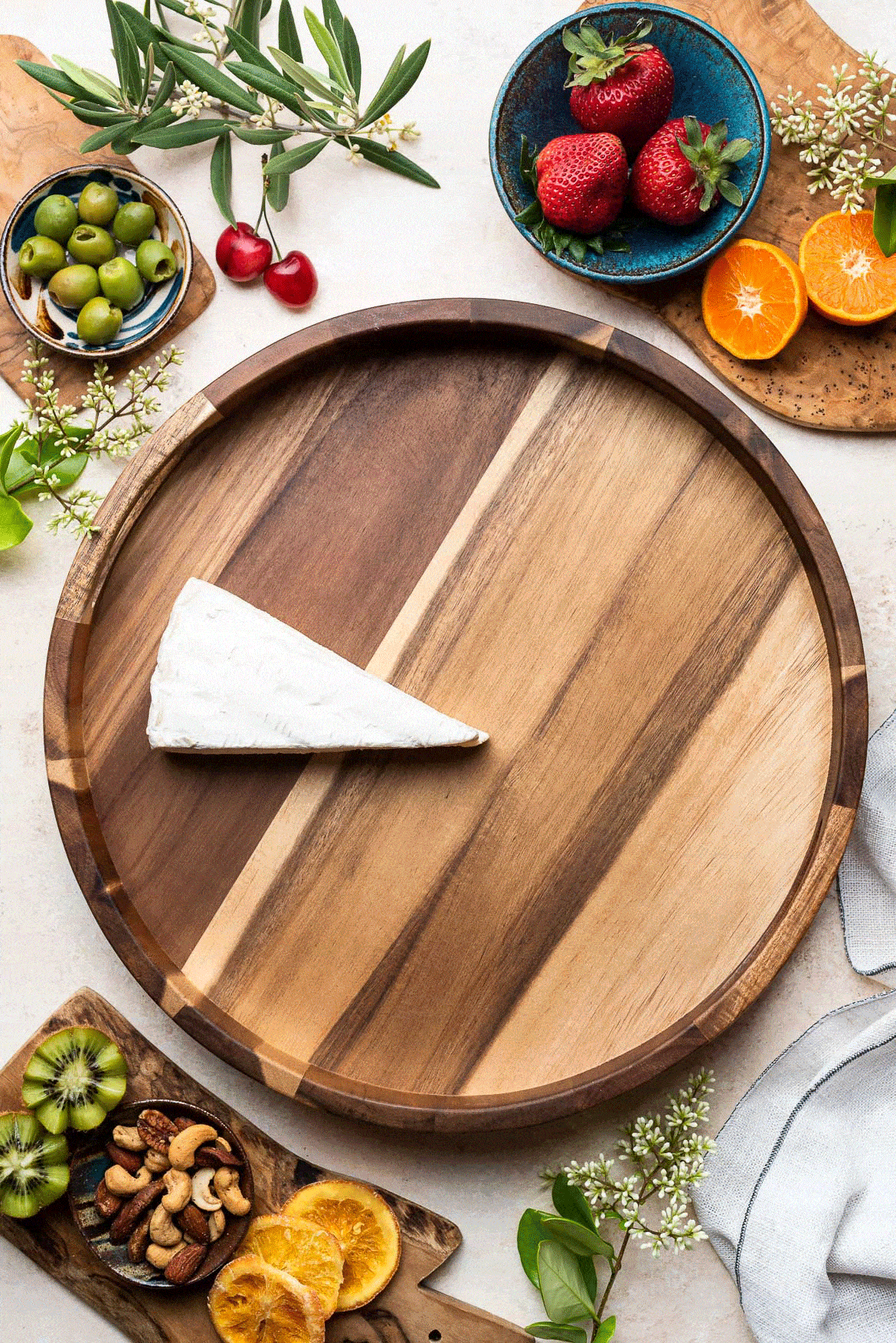 A GIF showing how to make a charcuterie board, step by step, on a wooden platter with meats and cheeses.