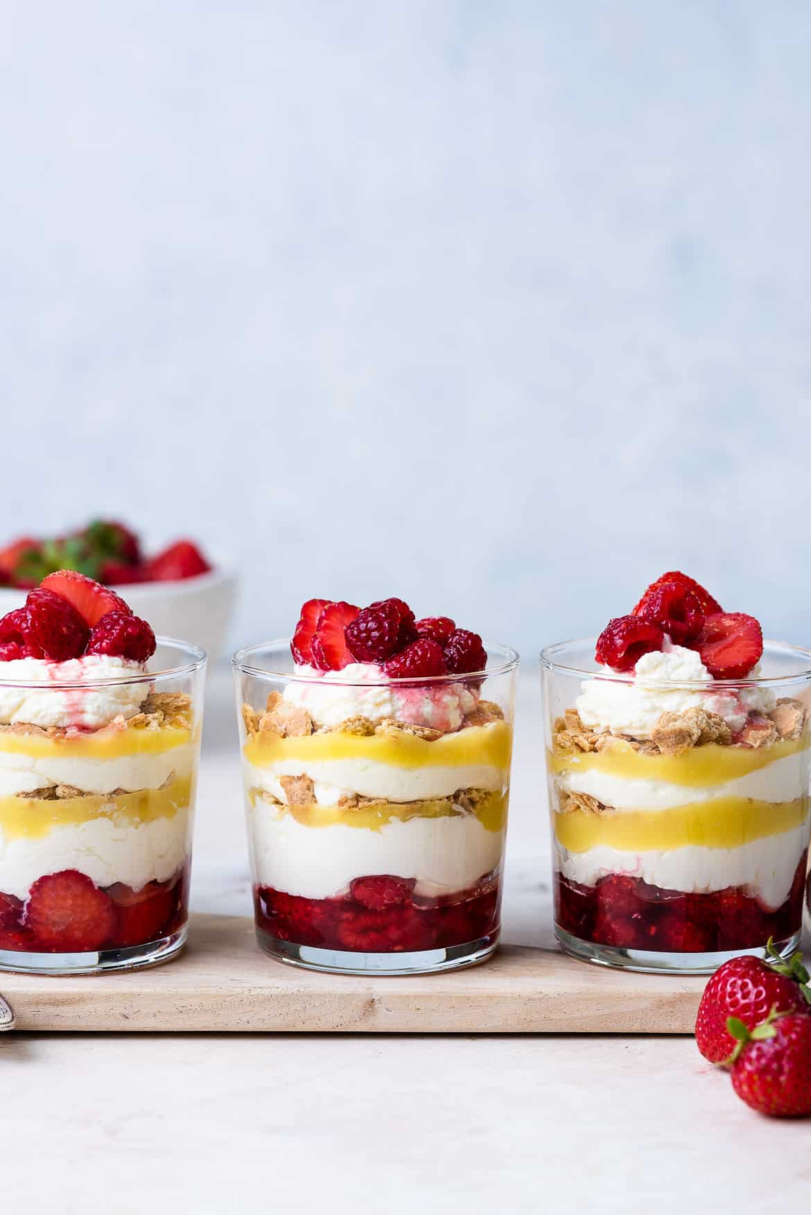 A row of Lemon-Berry Cheesecake Parfaits in glass cups.