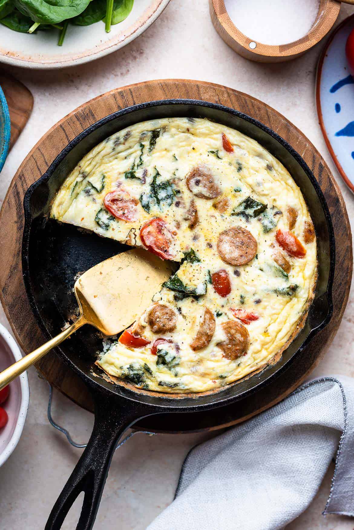 A Italian Sausage and Kale Frittata sliced in a cast iron skillet.