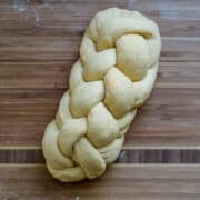 A braided Challah loaf on a wooden surface.