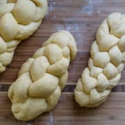 Three Braided Challah Loaves on a Wooden Surface.