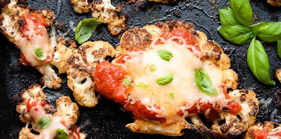 Baked Cauliflower Parmesan garnished with basil in a baking dish.