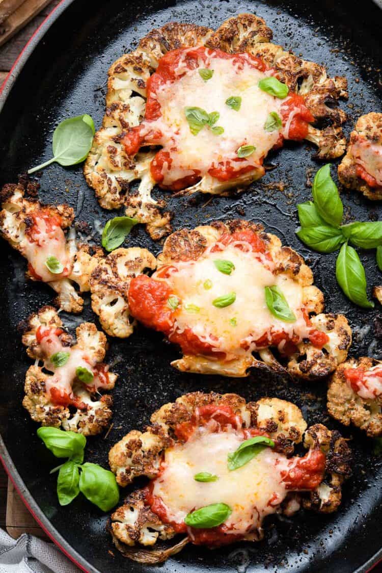 Baked Cauliflower Parmesan garnished with basil in a baking dish.