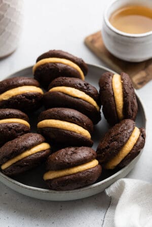 Chocolate Pumpkin Whoopie Pies in a light grey bowl with a cup of tea.