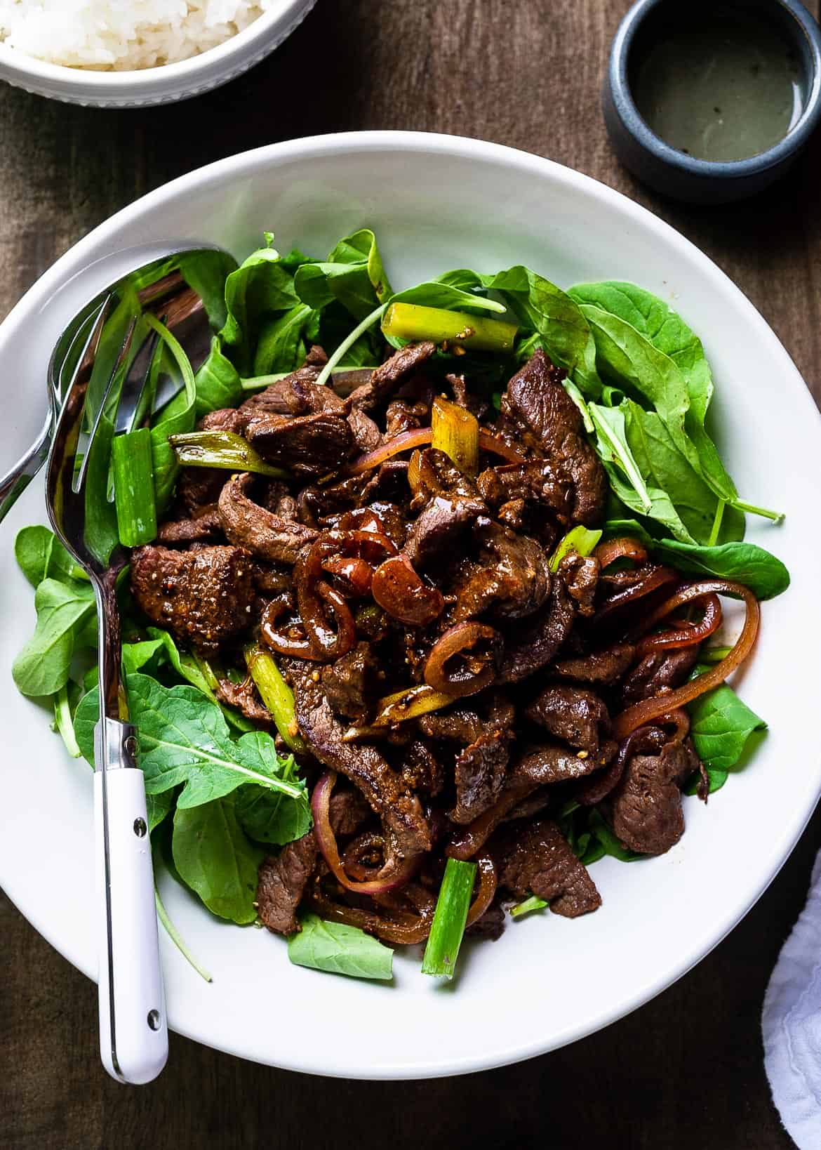 Strips of stir-fried beef, caramelized onions, and sauce served over fresh greens.