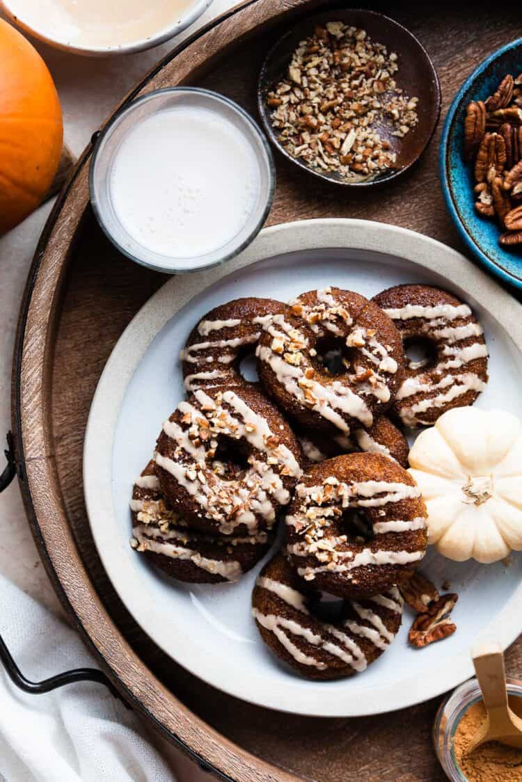 A stack of Baked Pumpkin Donuts with Almond Flour and Spiced Maple Glaze on a plate a tray.