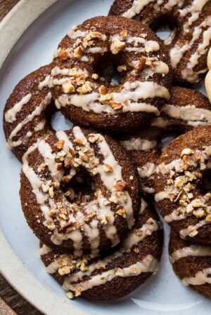 A stack of Baked Pumpkin Donuts with Almond Flour and Spiced Maple Glaze on a plate.