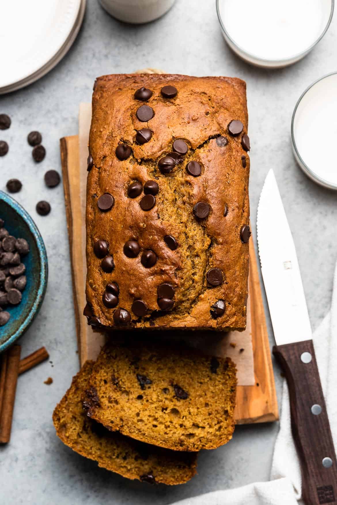 Slicing a loaf of Chocolate Chip Pumpkin Bread on a wooden board.
