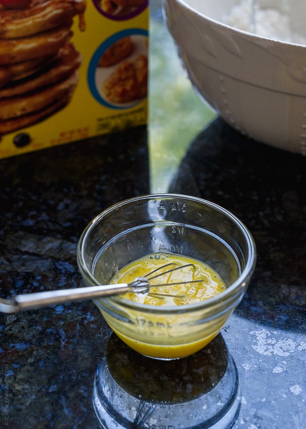 A small glass bowl with beaten egg an a whisk inside.