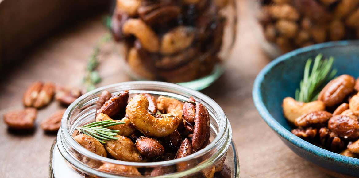 Spiced nuts in mason jars on a wooden tray.