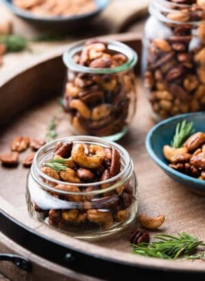 Spiced nuts in mason jars on a wooden tray.