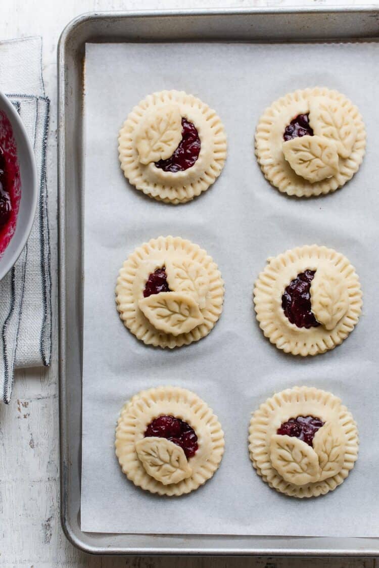 Cranberry Hand Pies formed before baking on a baking sheet.
