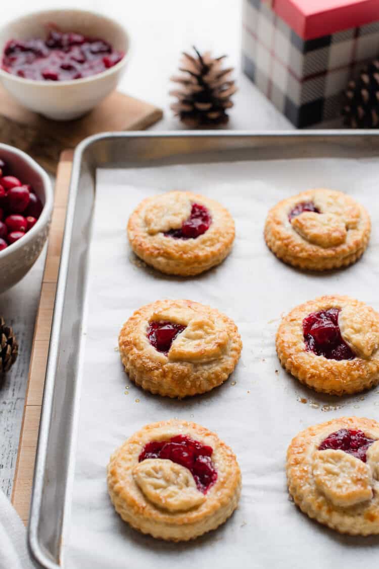 Cranberry Hand Pies cooling on a parchment lined baking sheet.