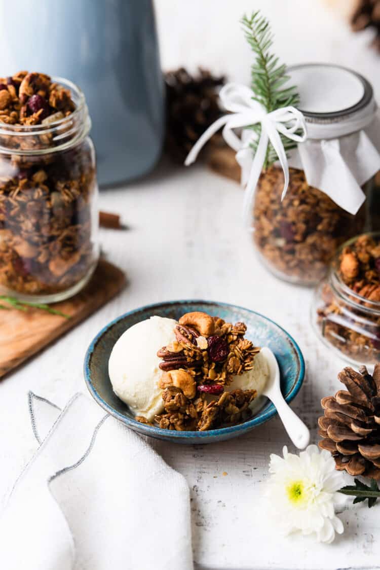 Gingerbread granola on eggnog ice cream in a blue bowl.