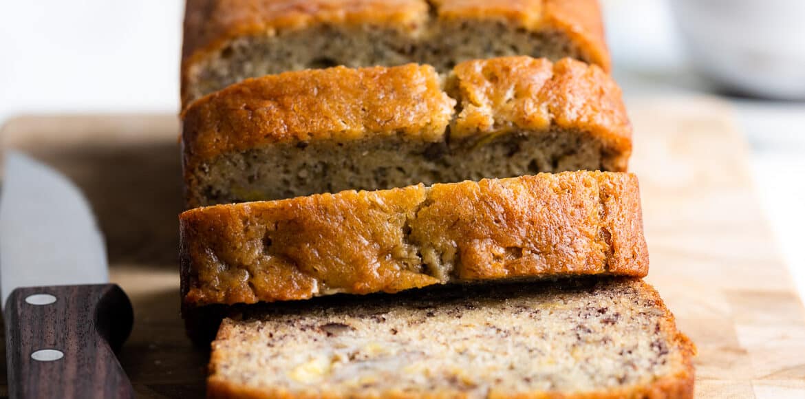 Slicing a loaf of Buttermilk Banana Bread.