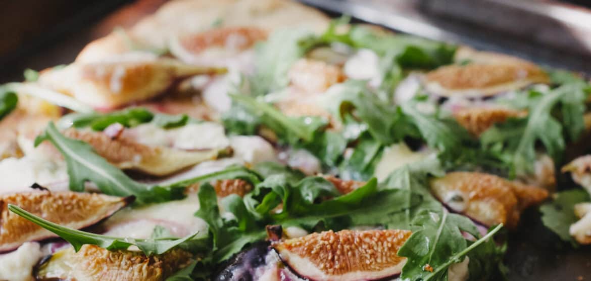 A homemade pizza topped with figs, arugula, blue cheese and jalapeno jam.