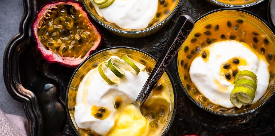 Passion Fruit Possets on a tray topped with coconut yogurt and a garnish of lime peel.
