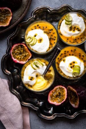 Passion Fruit Possets on a tray topped with coconut yogurt and a garnish of lime peel.