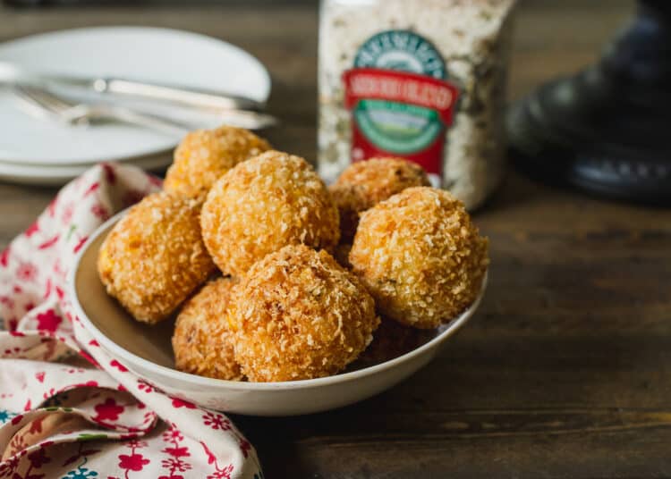 A freshly made bowl of risotto balls sitting on a table with a cloth napkin.