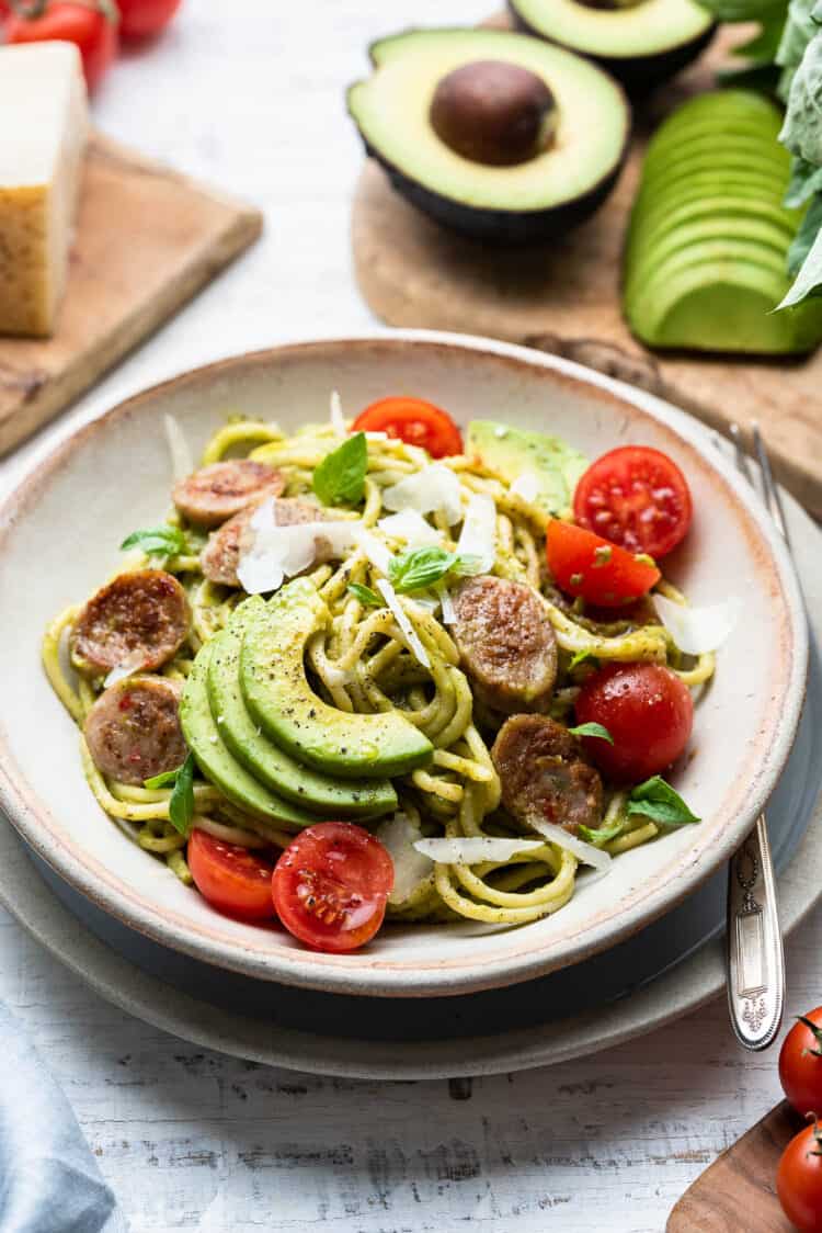 Avocado Pesto Pasta with Chicken Sausage and tomatoes in a bowl.