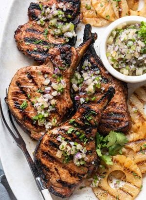 Grilled Pineapple Pork Chops on a platter with grilled pineapple and pineapple salsa.
