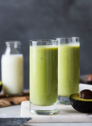 Avocado milk smoothie in two tall glasses.
