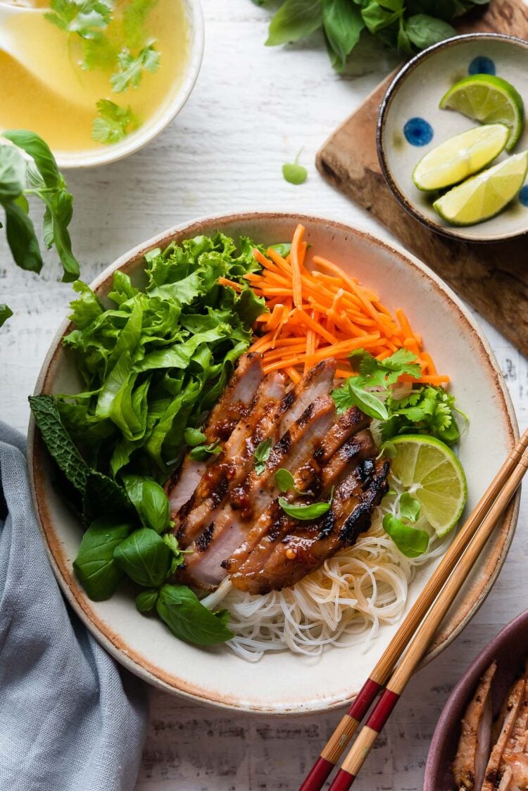 Vietnamese-style Grilled Pork Chops in a bowl on a bed of rice noodles and vegetables.