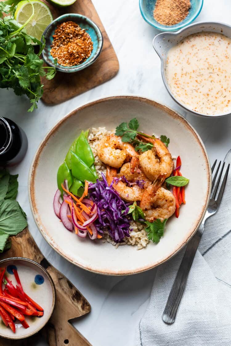 Thai-style Shrimp Bowls with brown rice, red cabbage, red onions, carrots, and snow peas served with Spicy Coconut Dressing on the side.